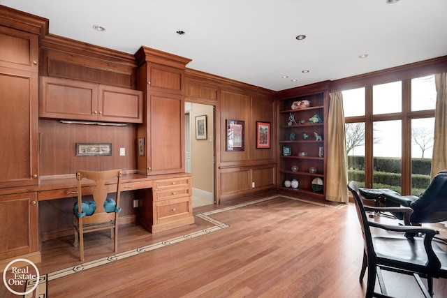 office space with built in desk, recessed lighting, wooden walls, crown molding, and light wood finished floors