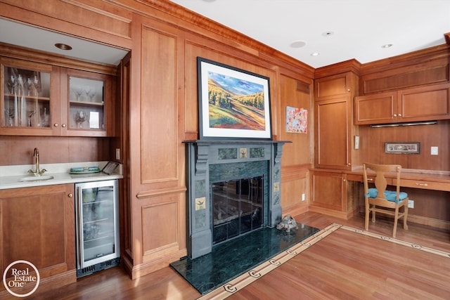 interior space featuring wood finished floors, beverage cooler, a premium fireplace, wet bar, and wood walls