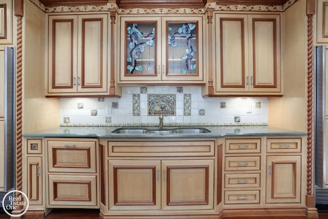 kitchen featuring a sink, glass insert cabinets, tasteful backsplash, and dark stone countertops