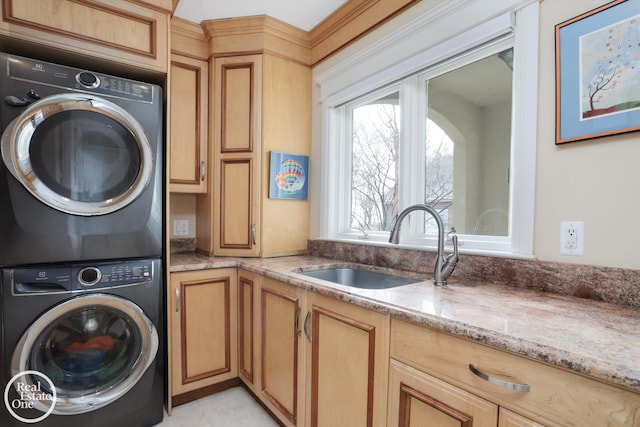 laundry area featuring stacked washer / dryer, cabinet space, and a sink