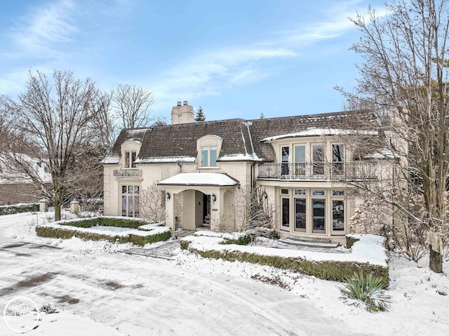 view of front of property featuring a balcony and a chimney