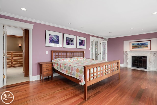 bedroom with crown molding, light wood-style flooring, recessed lighting, and a fireplace