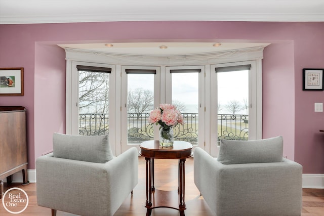 living area with baseboards, light wood finished floors, and ornamental molding