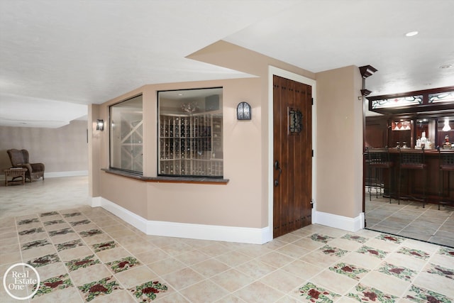 foyer entrance featuring baseboards, indoor bar, and tile patterned flooring