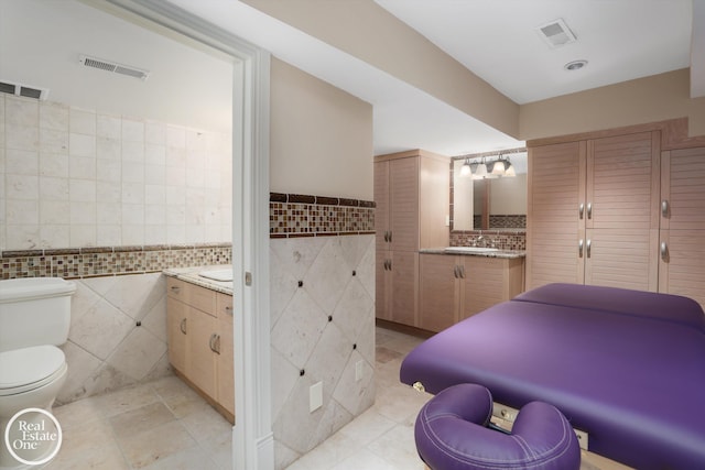 bathroom featuring visible vents, toilet, tile walls, and vanity