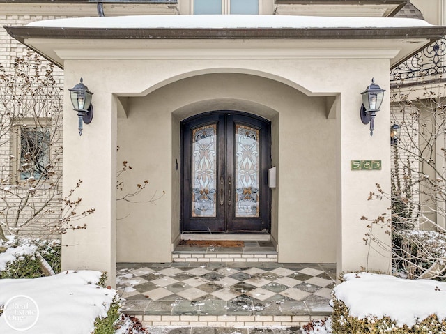 snow covered property entrance with stucco siding