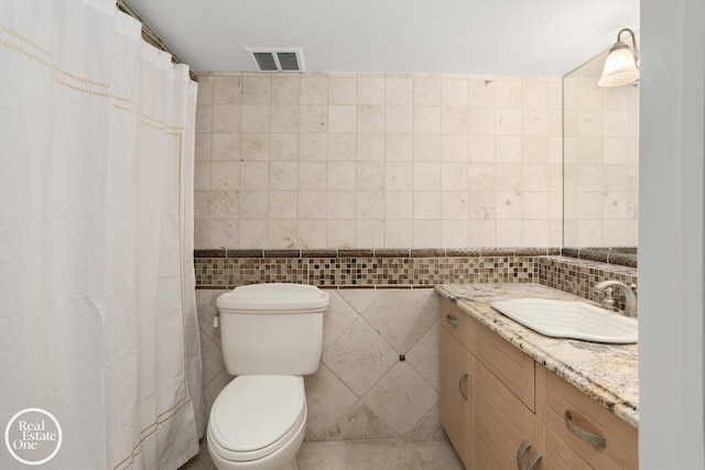 bathroom with visible vents, curtained shower, tile walls, toilet, and vanity