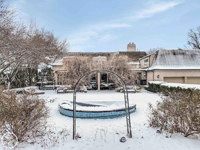 snow covered property featuring stucco siding and a chimney