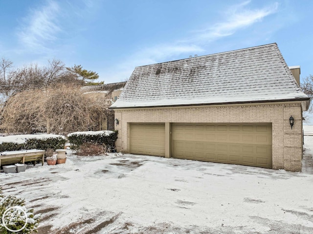 snow covered garage with a detached garage