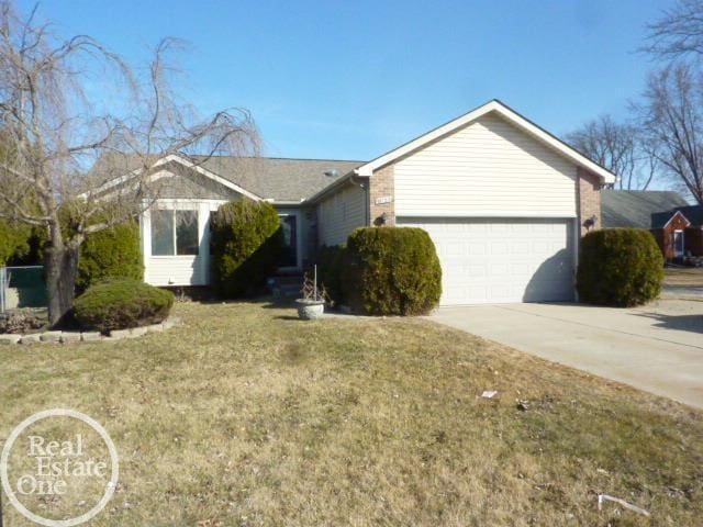 ranch-style home featuring a garage, concrete driveway, and a front lawn