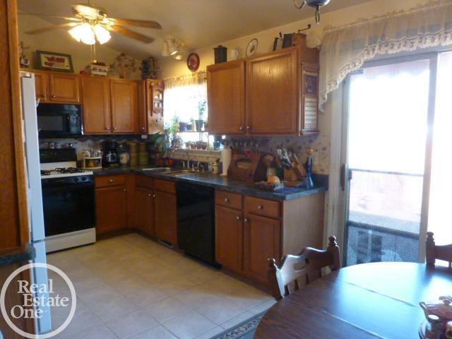 kitchen featuring brown cabinetry, black appliances, ceiling fan, and a sink