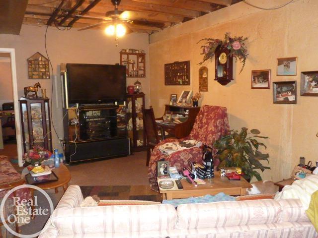 living area featuring beamed ceiling and ceiling fan