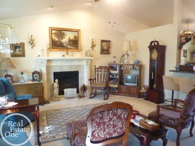 living area featuring a fireplace, lofted ceiling, and carpet floors