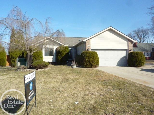 ranch-style house with concrete driveway, a garage, and a front lawn