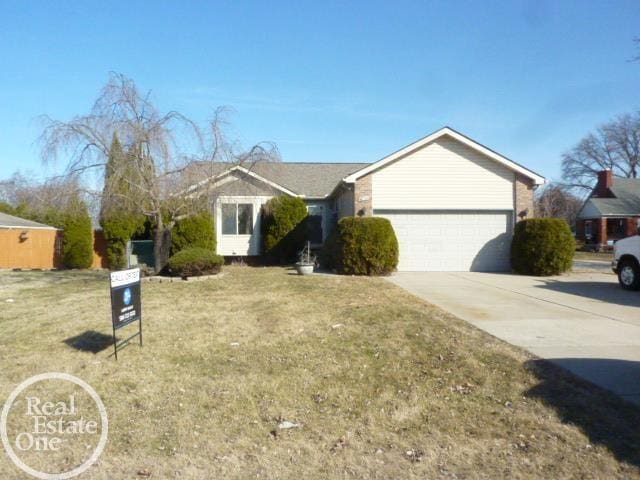 single story home featuring concrete driveway, a garage, and a front yard