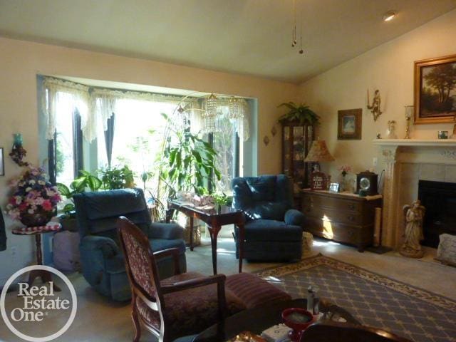 carpeted living room featuring a tiled fireplace and lofted ceiling