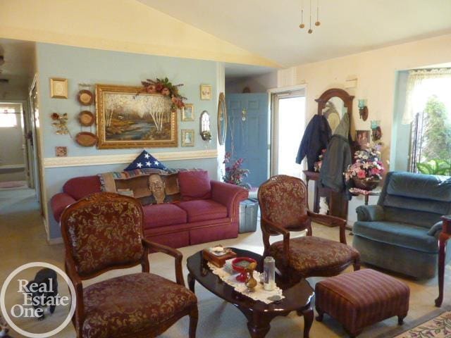 carpeted living area featuring plenty of natural light and vaulted ceiling