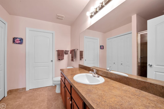 bathroom featuring toilet, a shower with door, a closet, baseboards, and vanity