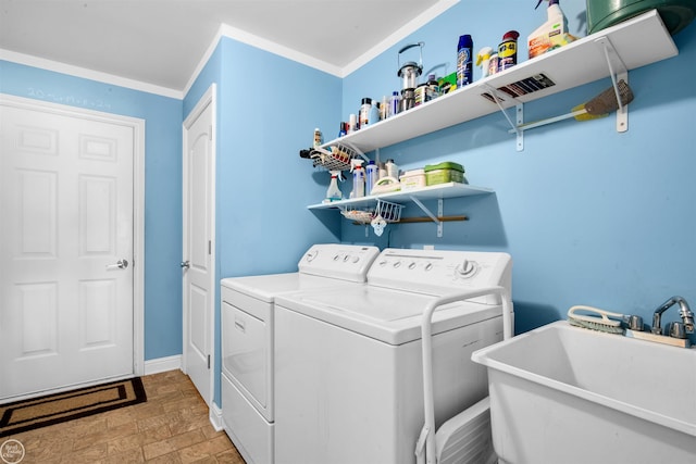 clothes washing area with baseboards, laundry area, a sink, crown molding, and washer and clothes dryer