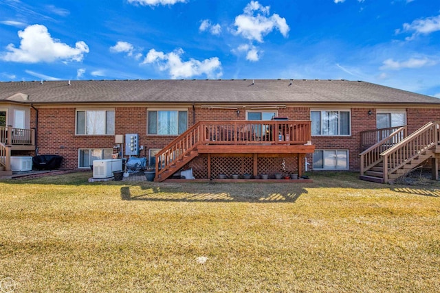 rear view of property featuring stairway, brick siding, a wooden deck, and a lawn