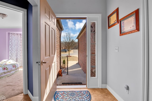 entryway featuring baseboards, light carpet, a healthy amount of sunlight, and light tile patterned flooring