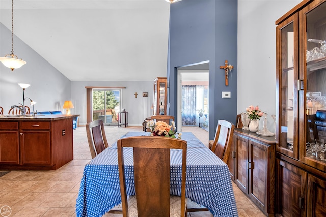 dining room featuring light tile patterned floors, baseboards, and high vaulted ceiling