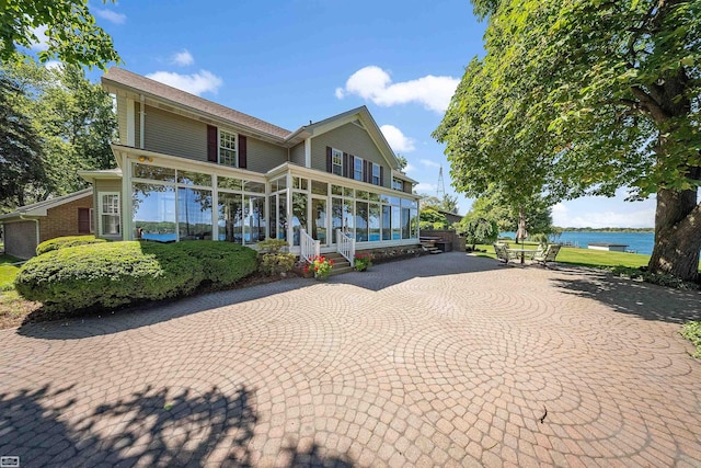 view of front of home featuring a water view, curved driveway, and a sunroom