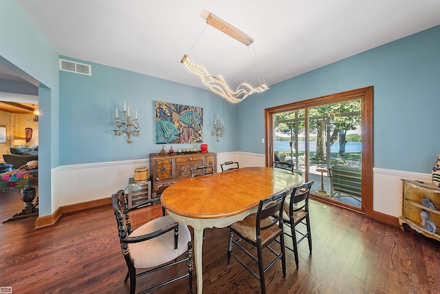 dining area with a notable chandelier, visible vents, baseboards, and wood finished floors