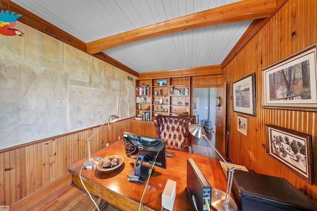 dining area with beam ceiling, built in features, wood walls, and wood finished floors