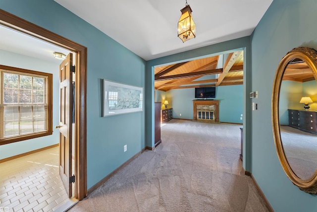 hallway featuring beam ceiling, carpet flooring, and baseboards