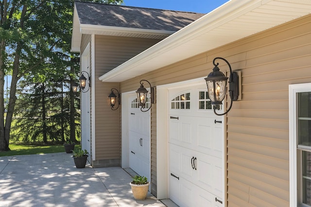 view of exterior entry with an attached garage and roof with shingles