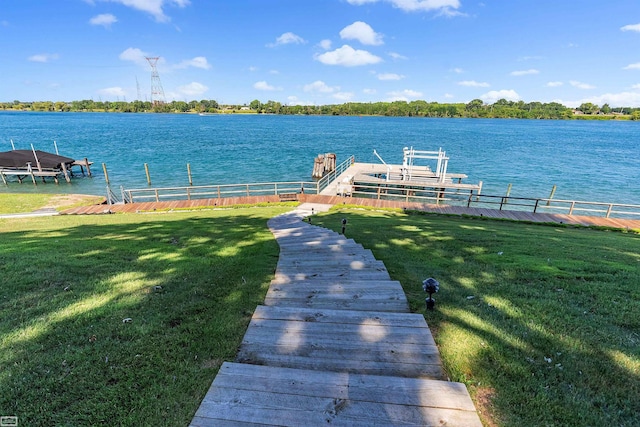 dock area with boat lift, a yard, and a water view