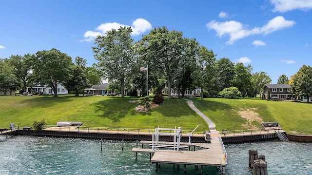 view of dock with a lawn and a water view