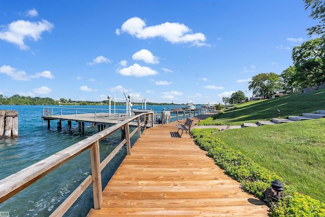 dock area featuring boat lift, a yard, and a water view