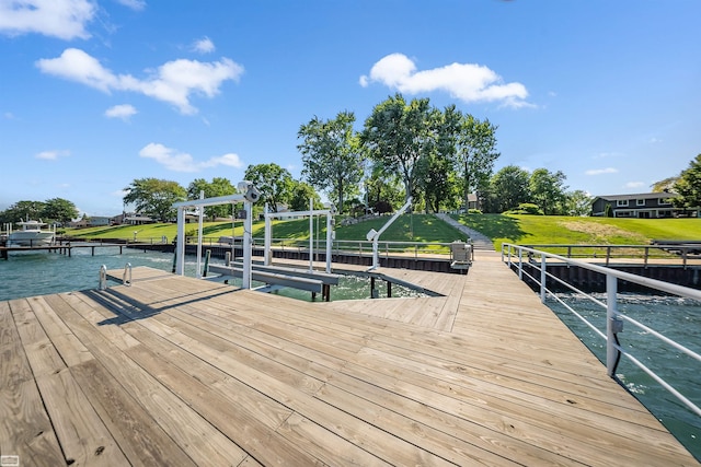 view of dock featuring boat lift, a water view, and a lawn