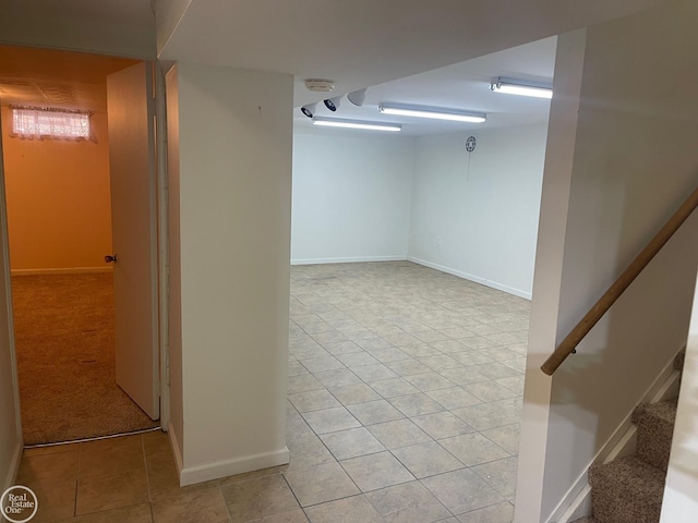 finished basement with light tile patterned flooring, stairs, and baseboards