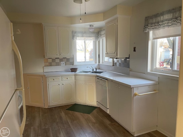 kitchen with dark wood-type flooring, light countertops, white cabinets, white appliances, and a sink