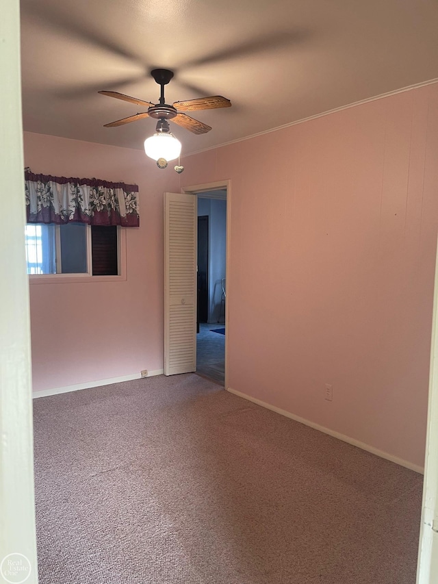 carpeted spare room with a ceiling fan, baseboards, and ornamental molding