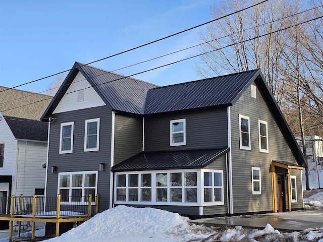 snow covered house featuring a deck, a patio area, and metal roof