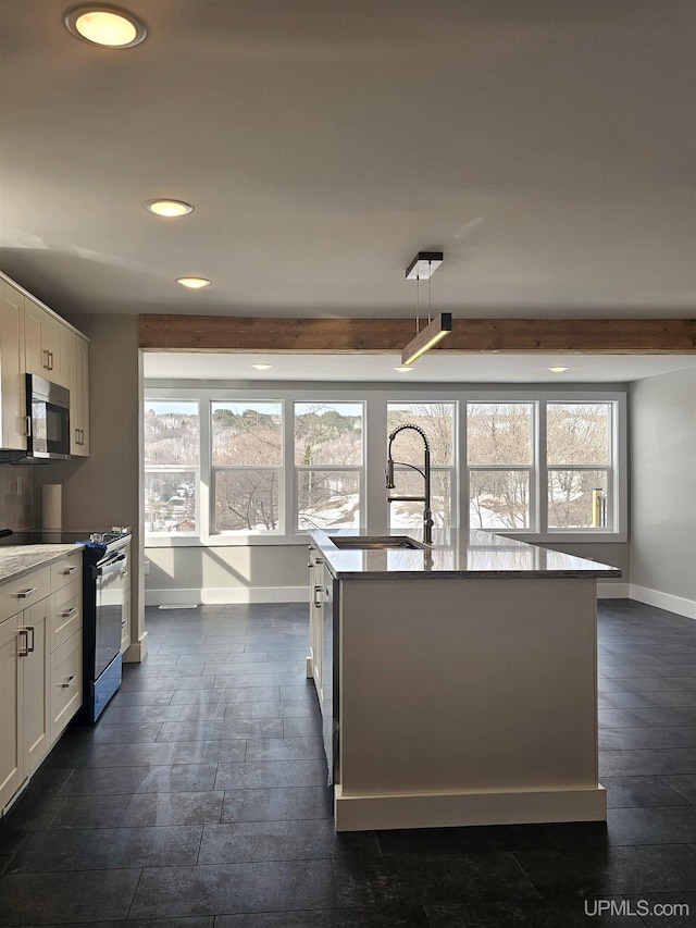 kitchen featuring a wealth of natural light, range with gas cooktop, a sink, and stainless steel microwave