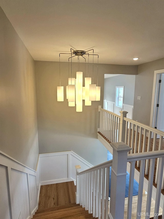 staircase featuring a decorative wall, wood finished floors, and wainscoting