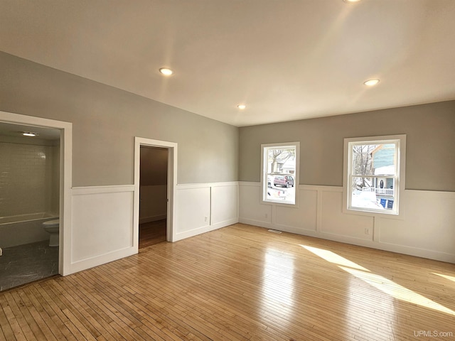 spare room featuring light wood finished floors, recessed lighting, and wainscoting