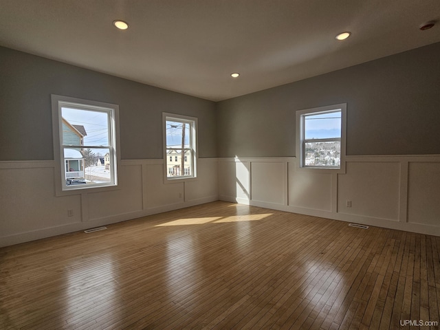 unfurnished room with hardwood / wood-style floors, recessed lighting, visible vents, and wainscoting