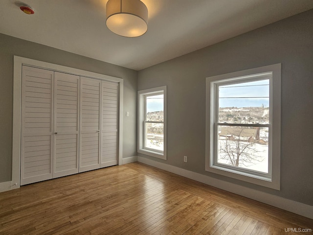 unfurnished bedroom featuring a closet, baseboards, and hardwood / wood-style flooring