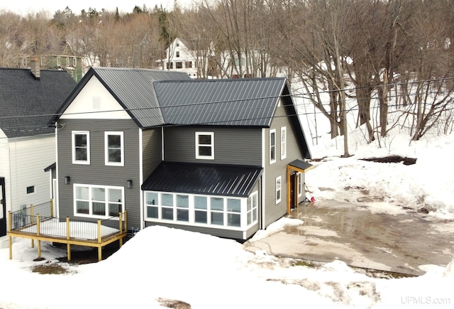 snow covered property featuring a wooden deck and metal roof