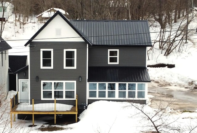 snow covered property featuring metal roof and a deck