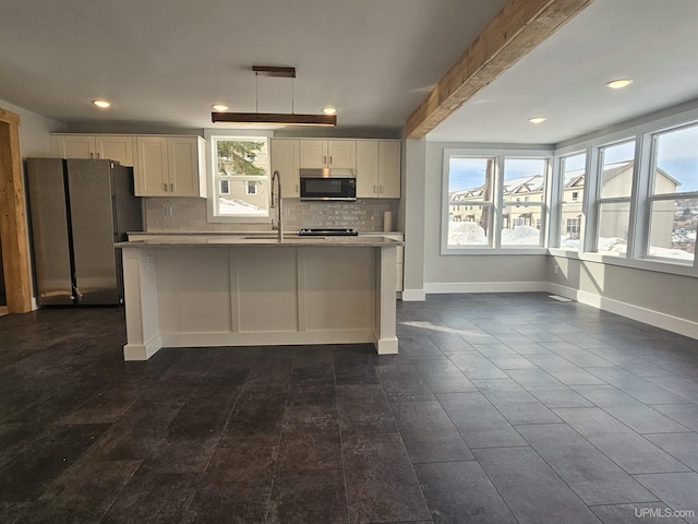 kitchen with a wealth of natural light, white cabinets, tasteful backsplash, and freestanding refrigerator