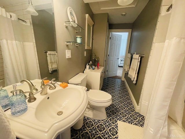 bathroom with a shower with curtain, toilet, tile patterned flooring, and a sink