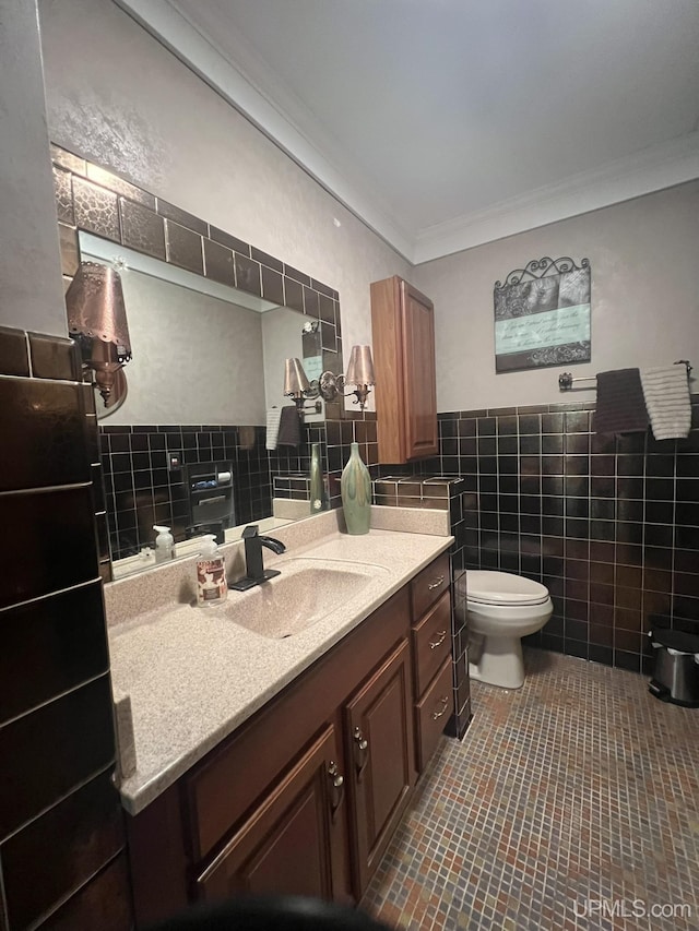 bathroom featuring toilet, vanity, ornamental molding, tile patterned floors, and tile walls