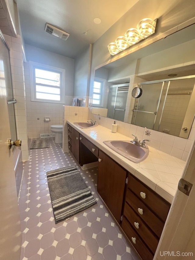 bathroom featuring a shower stall, visible vents, a wealth of natural light, and a sink